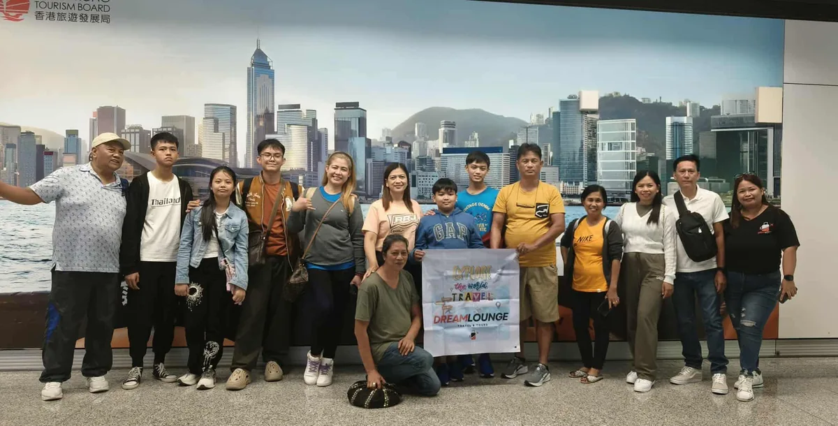 Dream Lounge tour group posing with a Hong Kong skyline backdrop